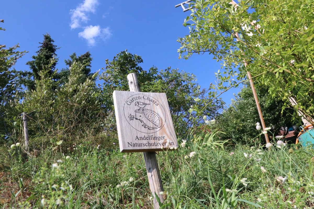 Wo in der Wiese eine Garten-Charta-Tafel steht