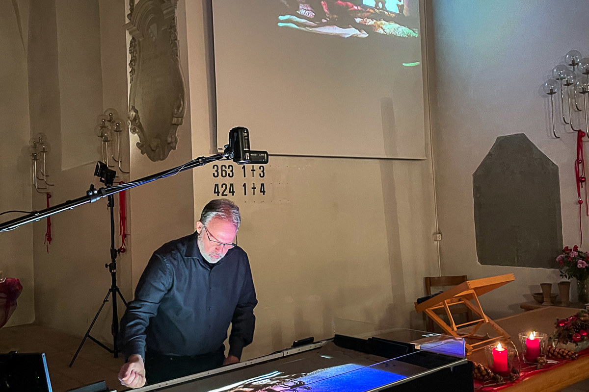 Frank Bigler gestaltete die Sandbilder zur Weihnachtsgeschichte auf einer Glasplatte, was live auf die Leinwand übertragen wurde.