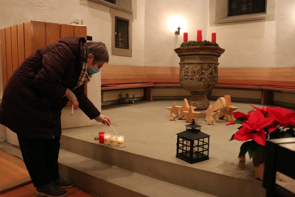 Eine Gottesdienstbesucherin nimmt das Friedenslicht nach Hause. Dieses befindet sich in der schwarzen Laterne (rechts im Bild)