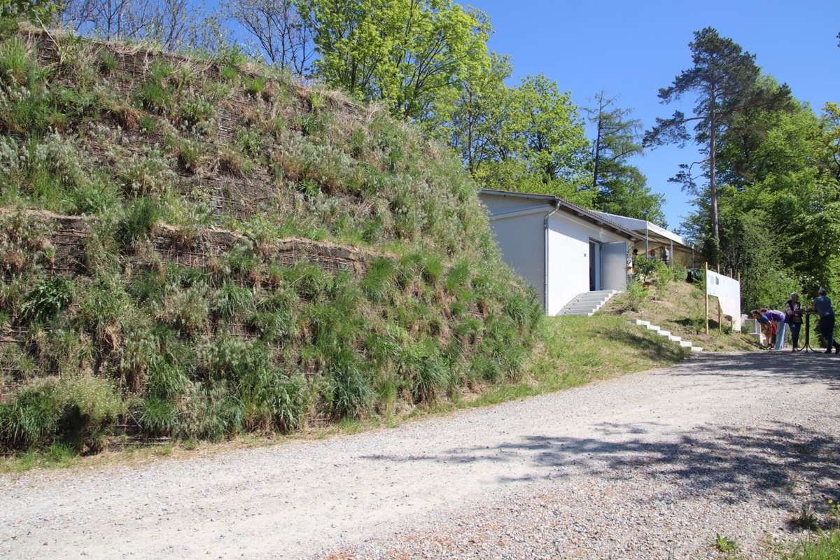 Die neue runde Wasserkammer ist überdeckt und mit einer Begrünung versehen. Hinter dem Betriebsgebäude befinden sich die vier alten Wasserkammern.